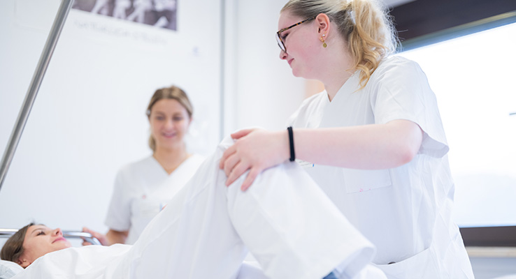 Pflegeschülerin übt unter Anleitung einer Praxisanleiterin die Mobilisation einer Patientin im Klinikum Kulmbach.